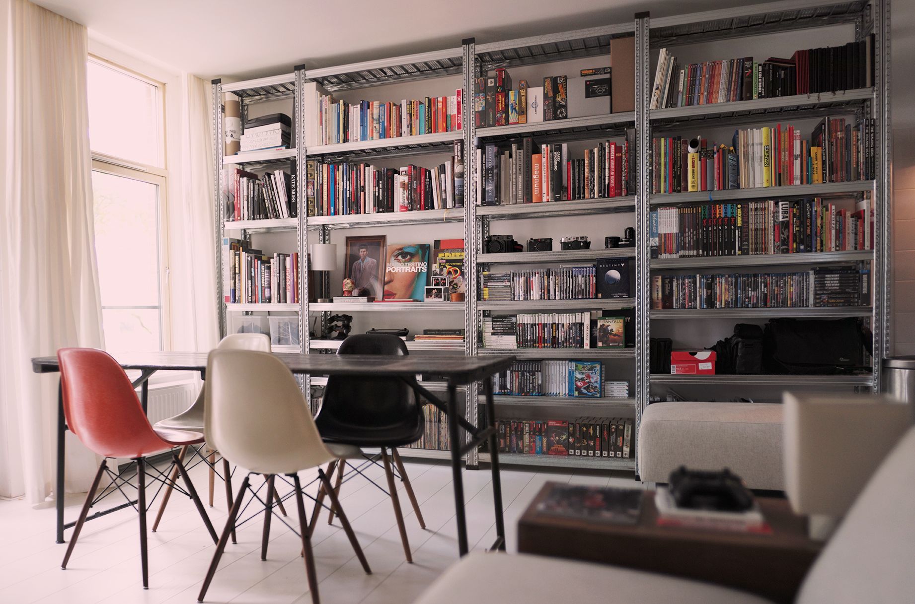 Wandvullende metalen boekenkast in een lichte woonkamer met eettafel