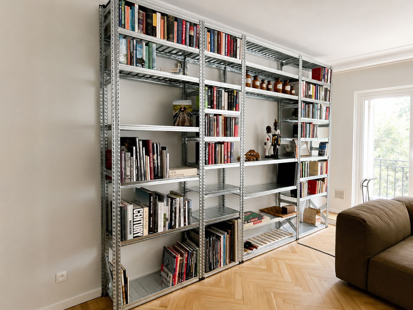 Grote open metalen boekenkast in een lichte ruimte met boeken en objecten